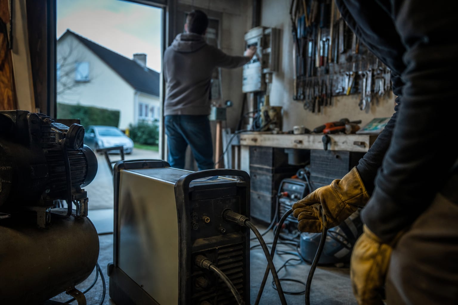 Mains branchant un poste à souder dans un atelier de garage français.