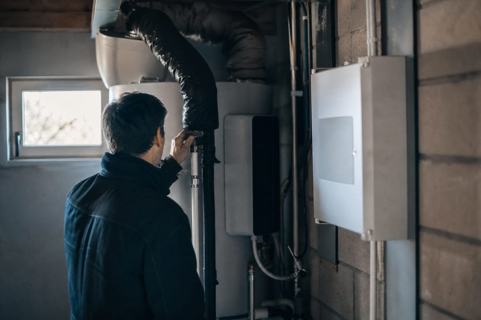 Technicien contrôlant le conduit d’air d’un chauffe-eau thermodynamique domestique.