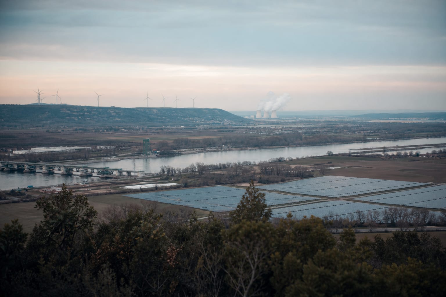 Panorama du Rhône mêlant centrale nucléaire, barrage, éoliennes et panneaux solaires.
