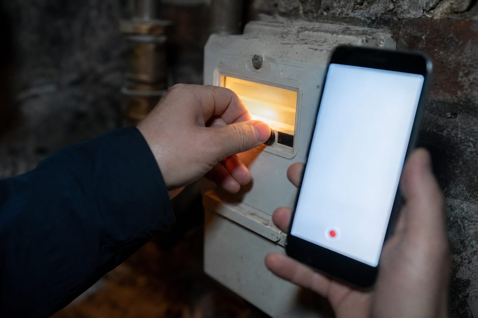 Gros plan d’une main relevant un compteur avec téléphone sans données visibles.