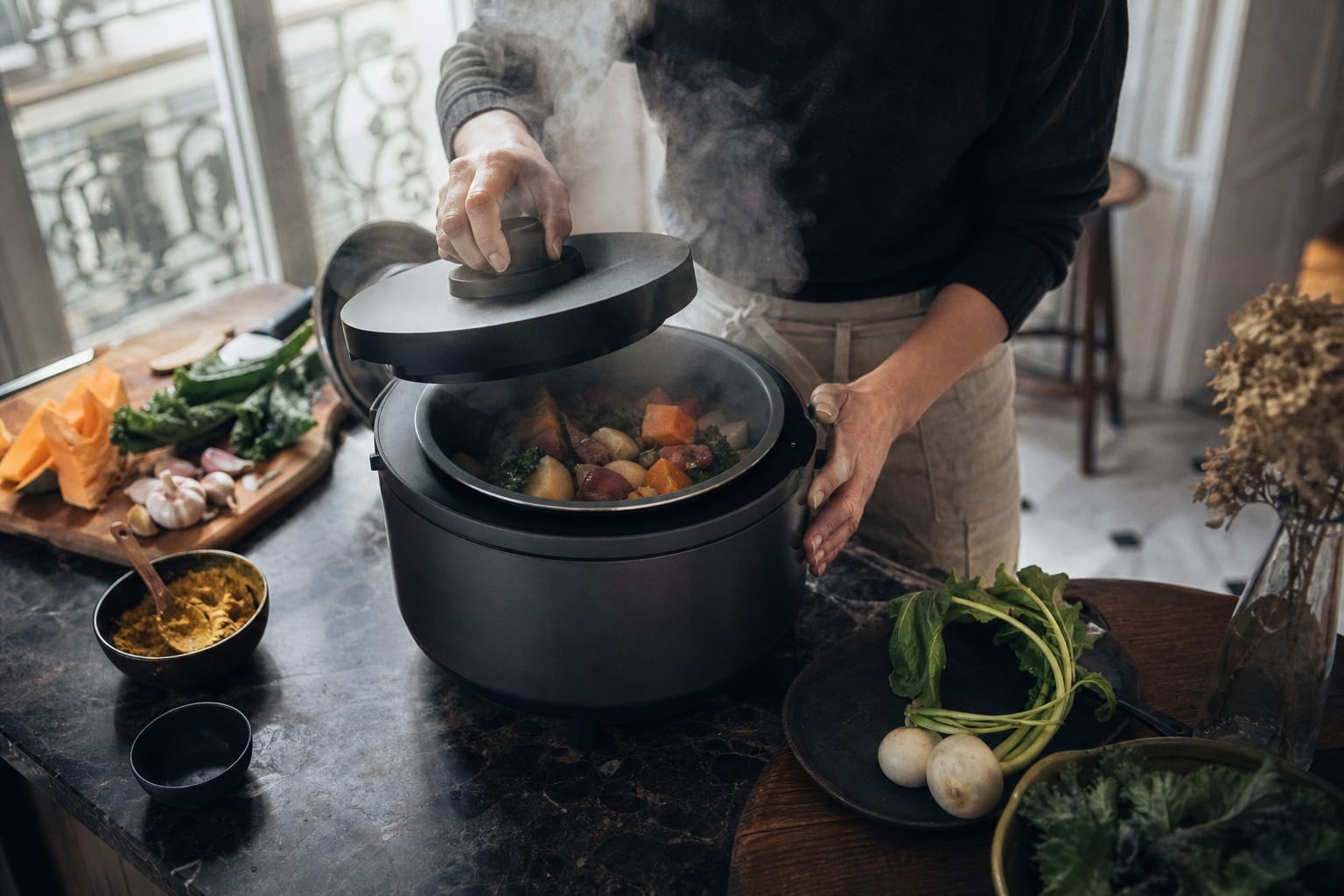 Mains fermant un robot cuiseur fumant dans une cuisine française.
