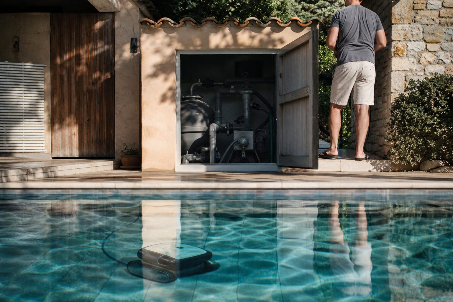 Robot électrique au fond d’une piscine, pompe de filtration visible à l’arrière.