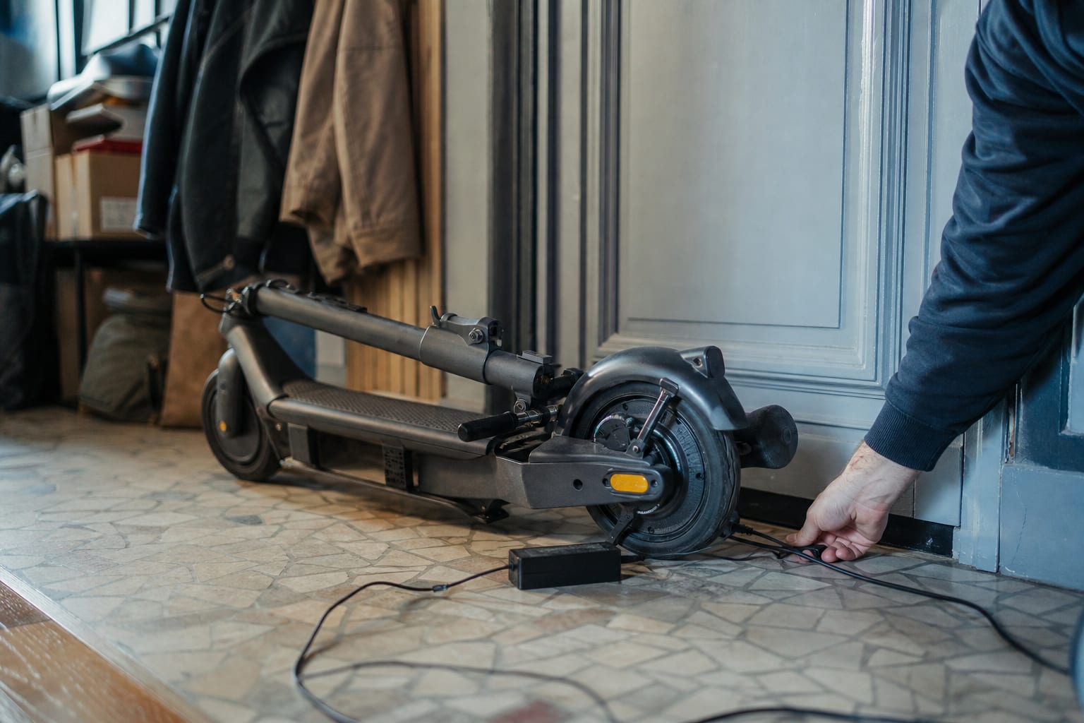 Trottinette pliée en charge sur sol dégagé dans une entrée.