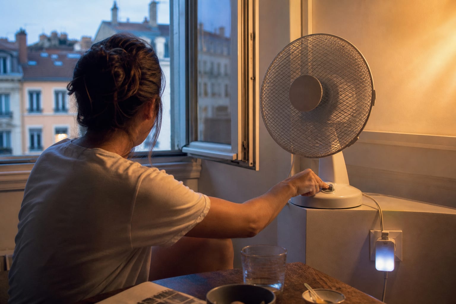 Petit ventilateur de table en marche dans un appartement lyonnais au crépuscule.