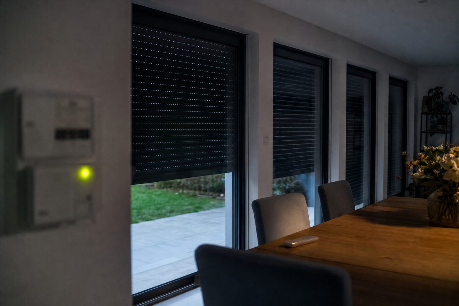 Volets fermés au crépuscule, télécommande et compteur électrique volontairement flou.