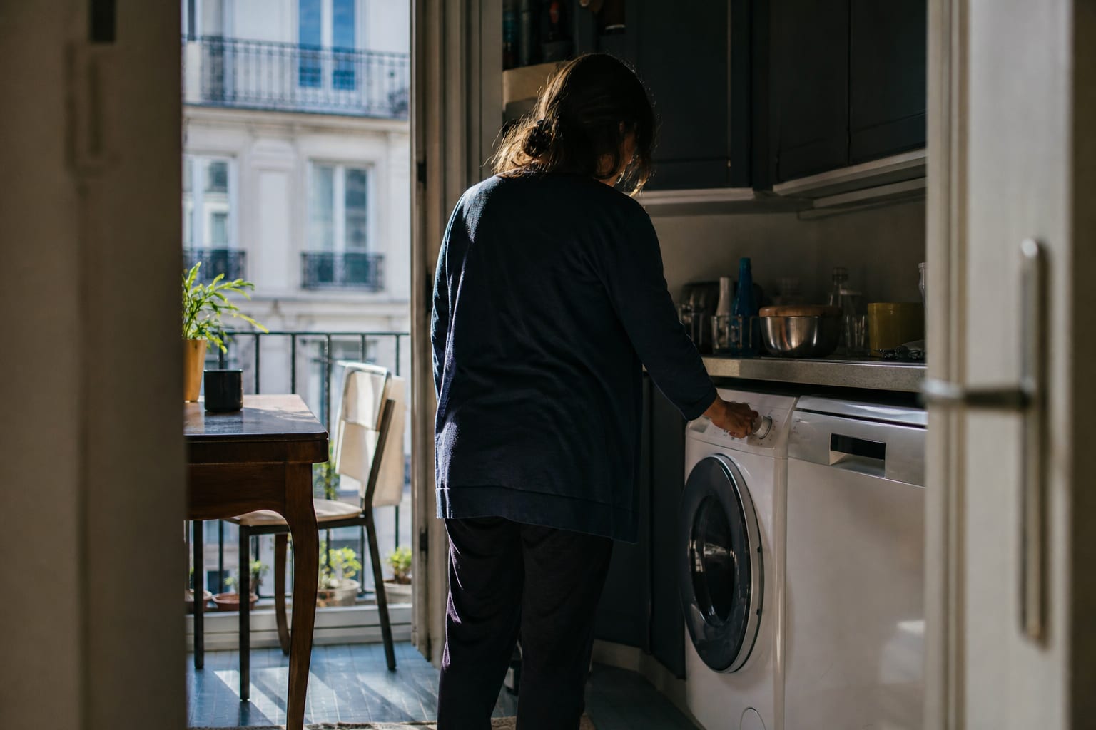 Habitant reprogrammant ses appareils dans un appartement lumineux en plein après-midi.