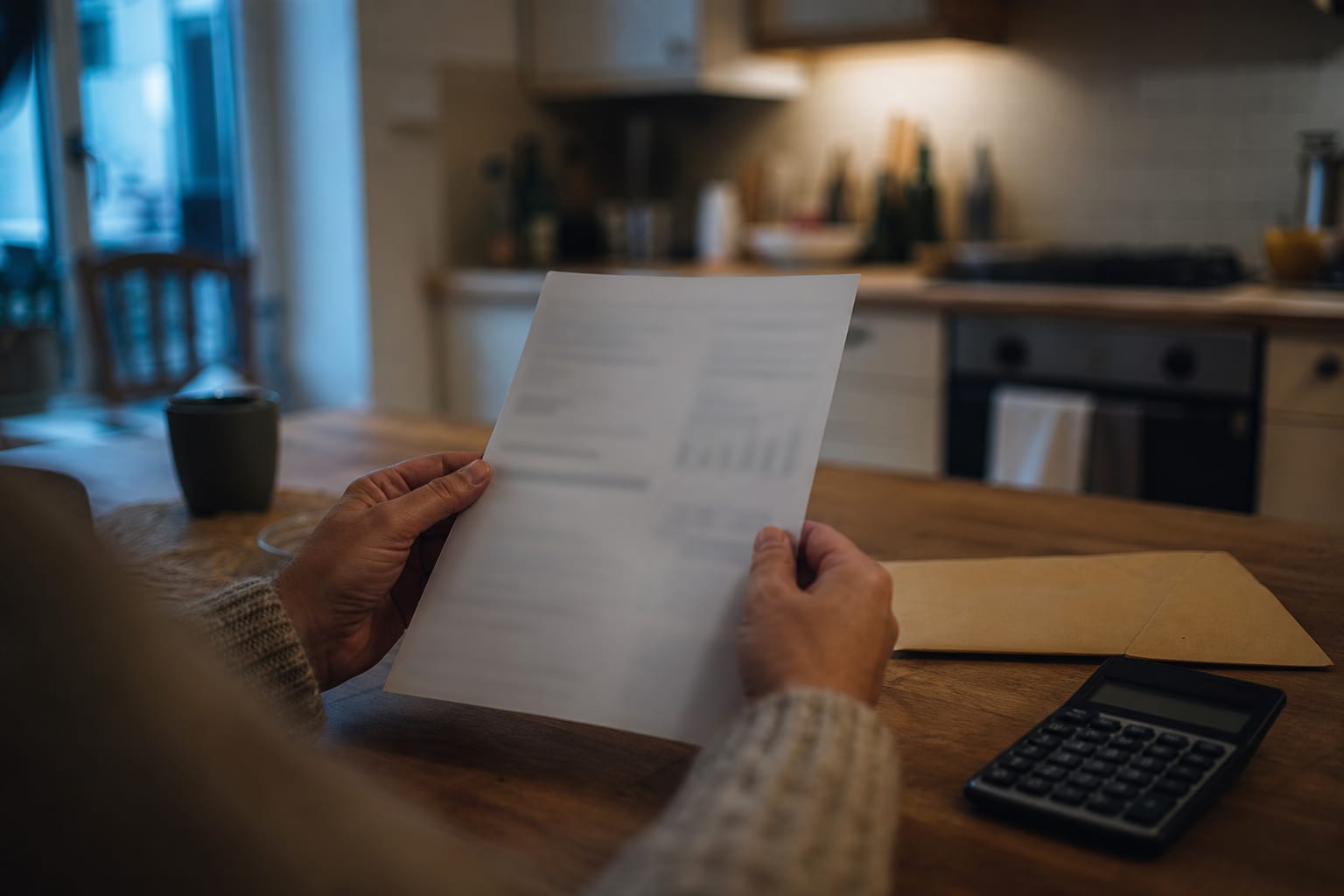 Mains consultant une facture illisible sans rabais apparent sur la table.